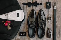 the groom's accessories are laid out neatly on the wooden floor, including shoes and watch