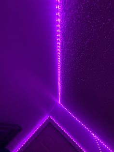 a room with purple lights on the ceiling and walls, along with a mirror in the corner