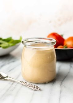 a glass jar filled with food sitting on top of a table next to a bowl of vegetables