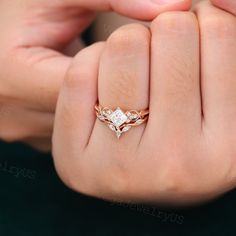 a woman's hand holding a diamond ring in her left hand, with the other hand on it