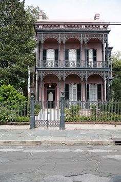 an old pink house with wrought iron fence