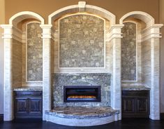 a fireplace in the middle of a room with columns on either side and an arched doorway