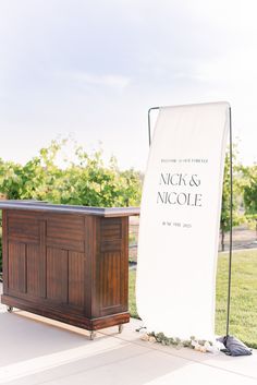 an outdoor bar set up for a wedding with a sign on the front and side