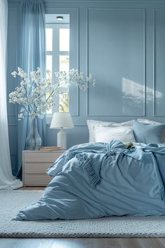 a bed with blue sheets and pillows in a bedroom next to a lamp, dresser and window