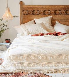 the bed is made with white linens and fringed pillows on top of it