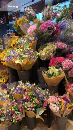 a bunch of flowers that are sitting on the ground in front of a store window