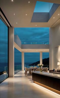 a living room filled with furniture next to a large glass window overlooking the ocean at night