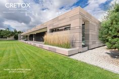 a house that is in the middle of a grass covered field with trees and bushes around it