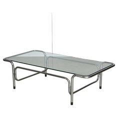 Italian vintage coffee table, expertly crafted with stunning, bold chromed curves that are sure to captivate and impress. The low profile, glass top, and elongated shape of this piece create a sense of fluidity and movement, adding a touch of sophistication and elegance to any living space. Elevate your home decor with this unique and timeless statement piece that effortlessly combines form and function. Chrome And Glass Coffee Table, Low Coffee Table, Italian Mid Century Modern, Coffee Cocktails, Coffee And Cocktail Tables, Coffee Table Vintage, Glass Coffee Table, Modern Glass, Vintage Coffee