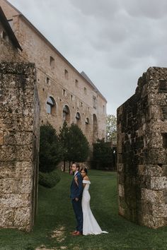 a bride and groom standing in front of an old building