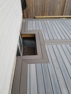 an open window on the side of a wooden deck next to a wall and fence