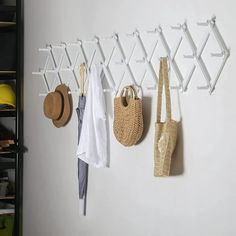 several hats and purses are hanging on the wall next to each other with hooks