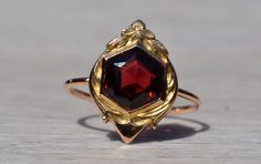 The West Park: Antique Hexagonal Shaped Garnet with Art Nouveau Frame. The ring centers on a specialty cut hexagonal garnet between an Art Nouveau frame of floral motif. Crafted in 14 karat rose gold with 18 karat yellow gold wash, the ring is hallmarked by its designer yet we have not quite identified the maker. The ring is currently a finger size 6 1/2 yet can be adjusted to any finger size for an additional charge by request. Love this piece, but don't have the money to spend right now? We of Formal Octagon Ruby Jewelry, Elegant Faceted Ruby Ring In Yellow Gold, Elegant Yellow Gold Faceted Ruby Ring, Elegant Hexagon Jewelry With Polished Finish, Elegant Faceted Ruby Ring For Formal Occasions, Elegant Formal Faceted Ruby Ring, Hexagon Faceted Formal Jewelry, Elegant Octagon Faceted Rings, Elegant Hexagon Faceted Rings