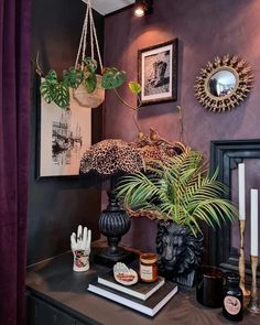 a room with purple walls and pictures on the wall, plants in vases and other decorations