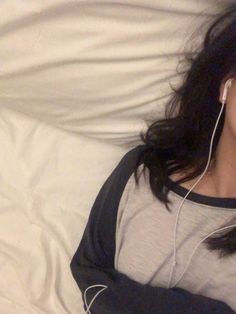 a woman laying in bed listening to headphones