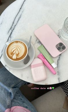 there is a cup of coffee on the table next to some cell phones and a phone case