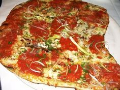 a large pizza with lots of toppings sitting on top of a white platter