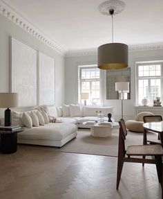 a living room filled with furniture and a table in front of two windows on either side of the couch