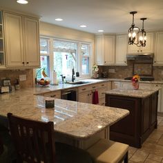 a large kitchen with white cabinets and marble counter tops, an island in the middle