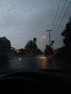 rain is falling down on the windshield of a car