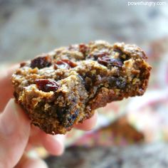 a hand holding up a cookie with raisins and nuts on it's side