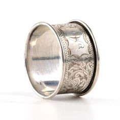 a silver ring with an intricate design on the outside and inside, sitting on a white surface