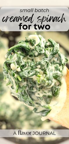 a wooden spoon filled with spinach on top of a white sauce in a pan