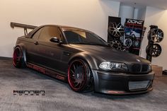 a black car parked in a garage next to some tires and rims on the floor