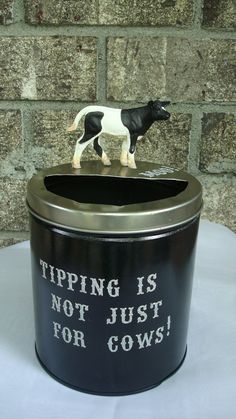 a black and white cow figurine sitting on top of a trash can that says tipping is not just for cows