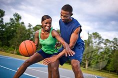 a man and woman playing basketball on an outdoor court