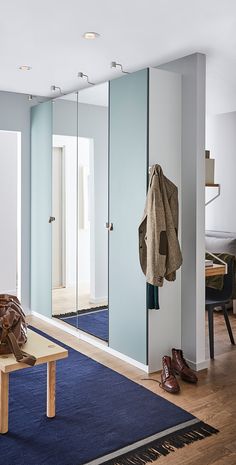 a room with a bench, coat rack and mirror on the wall next to it