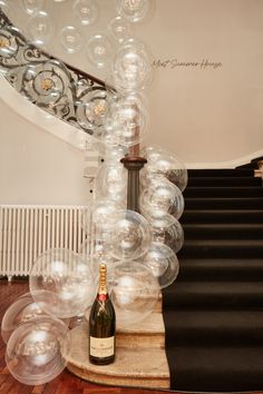 a bottle of champagne sitting on top of a wooden table next to some clear bubbles