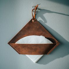 a leather pouch hanging on the wall with a pair of scissors and napkins in it