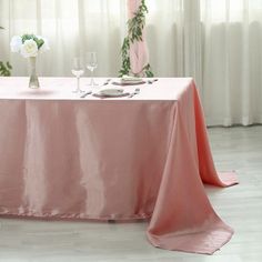 the table is covered with pink cloths and place settings for two people to sit at