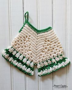 a crocheted green and white dress hanging on a wall