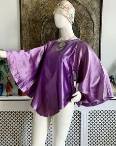 💜 Beautiful vintage late 1960s to early 1970s purple slippery satin tunic top.  Features wide angel sleeves, A-line shape, rounded front and back bottom hem, boat neckline finished with purple velvet. Handmade to a very good standard 💜 💜 There is a very faint area of colour variation on the front but it's so faint you really have to look hard to see it. This does not detract from the beauty of this garment though 💜  💜Fits sizes XS-Small. Best for bust up to 34 inches (18 inches across seam to seam). Length approximately 30 inches shoulder to longest point at hem 💜  Bust: best for up to 34 inches Length: 30 inches approx. shoulder to bottom hem ANY ACCESSORIES SHOWN IN THE PHOTOS ARE NOT INCLUDED IN THE SALE UNLESS OTHERWISE STATED. ♡ Facebook: https://www.facebook.com/VicAndBertieVin Purple Satin Top For Spring, Spring Purple Satin Top, Purple Silk Evening Top, Purple Bohemian Party Tops, Purple Bohemian Top For Party, Purple Satin Party Top, Purple Silk Party Tops, Satin Tunic, Violet Vintage