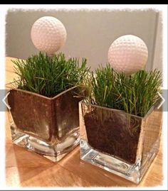 two glass vases with grass and golf balls in them