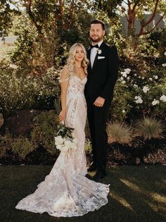 a bride and groom posing for a photo in front of some bushes at their wedding