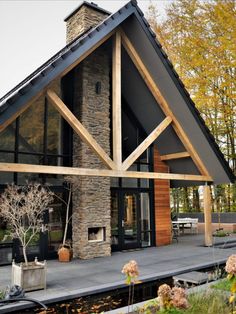 een prachtig huis met houten accenten. Het huis heeft een enorm hoge haard met Steenstrips erop bekleedt. Het is een bosvilla en een echte eyecatcher Woodland House, Suburban House, Modern House Exterior Design, House Exterior Design, A Frame House, Modern Cabin, Pole Barn Homes, Dream House Exterior