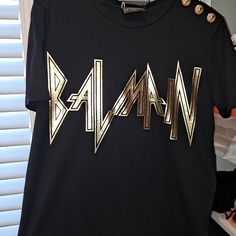 Authentic Balmain Cotton Tee With Gold Lettering And Gold Balmain Buttons. Exclusive Made For Saks. Size 42. New With Tags Black Designer Logo Crew Neck Top, Black Crew Neck Tops With Designer Logo, Black Crew Neck Top With Designer Logo, Luxury Black Tops With Letter Print, Luxury Black Top With Logo Print, Luxury Black Top With Graphic Print, Luxury Gold Tops With Graphic Print, Luxury Gold Top With Graphic Print, Designer Black Tops With Logo Print