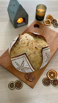 a loaf of bread sitting on top of a cutting board next to sliced oranges