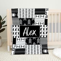 a black and white blanket with the word alex on it in front of a crib