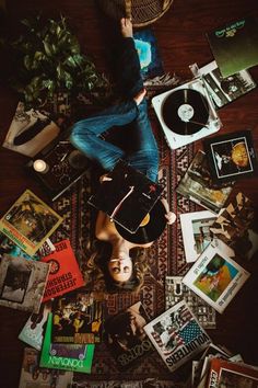 a woman laying on top of a wooden floor covered in books and cds next to a record player