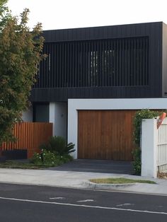 a black and white house with wooden garage doors