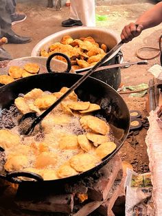 two pans filled with food sitting on top of a wooden table next to people