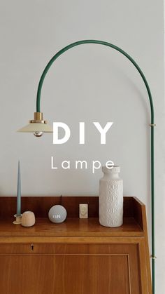 a lamp on top of a wooden dresser next to a white vase and other items