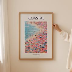 a woman standing in front of a poster on the wall next to a window with an ocean view