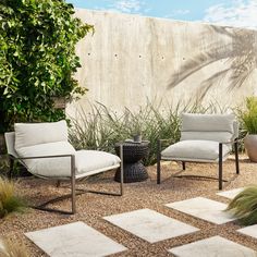 two chairs and a table in a small courtyard area with stone pavers on the ground