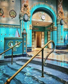 the inside of a building with blue walls and gold railings leading up to an entrance