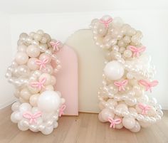 balloons are arranged in the shape of an arch with pink bows and ribbons on them